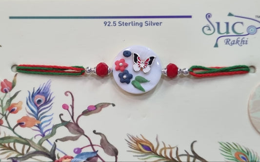 Silver rakhi with butterfly and flower design on a decorated card